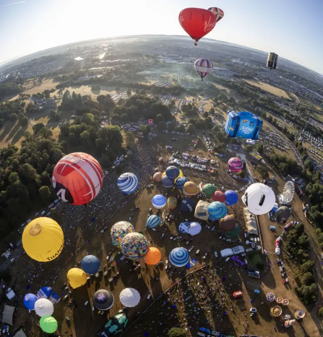 An aerial shot of the Bristol Balloon Fiesta showing many colourful hot air balloons taking off from Ashton Court