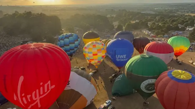 A view over balloons from the top while the sun is shining on them.