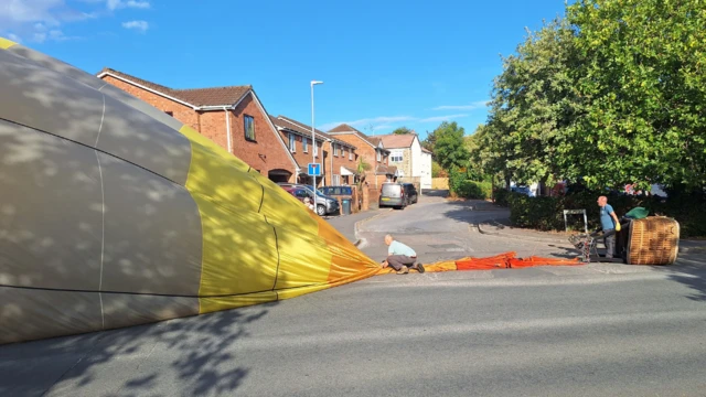 A hot air balloon ins being deflated on a residential road.