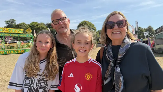 A family with two young girls is smiling at the camera.