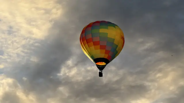 A colourful balloon is seen against a cloudy morning sky.