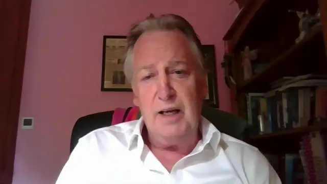 Paul Williams wears a white shirt while sitting in a pink room.