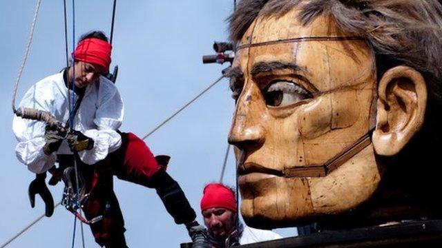 Dozens of people work the ropes of the giants to operate them.