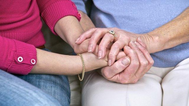 Carer holding the hand of an elderly woman