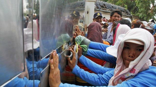 Garment workers push against the gates of a factory