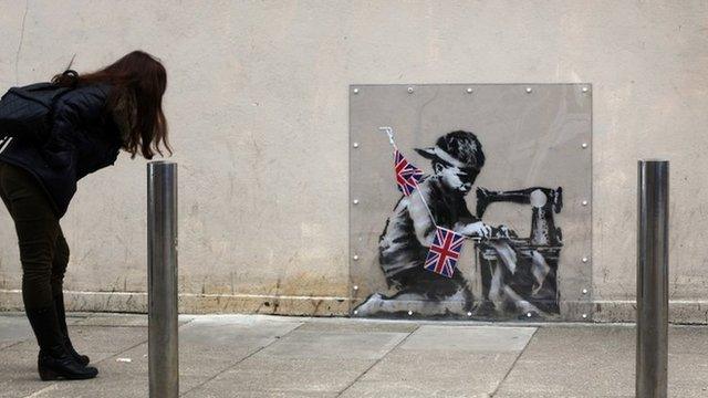 Woman looking at Banksy mural