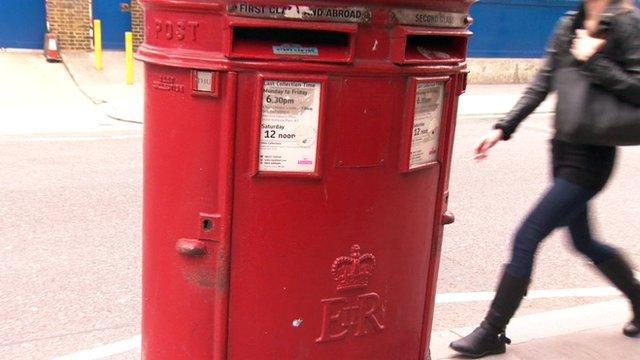 Woman walks behind post box