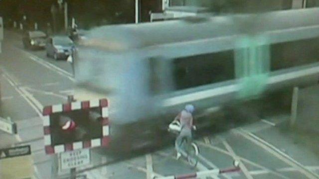 Woman on bike narrowly missing being hit by train at level crossing