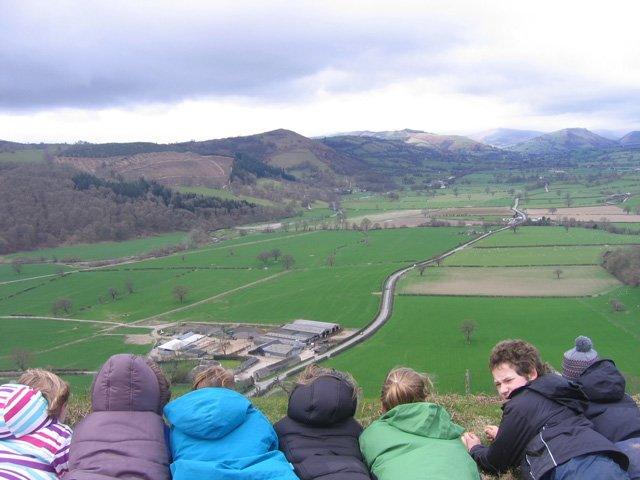 Children look over towards the Llwyn Bryn Dinas Hillfort in Powys