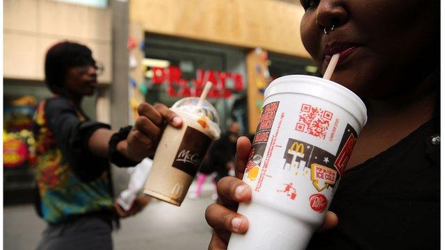 A woman drinking a super-sized soda