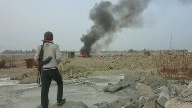 Man with gun watches fire in distance