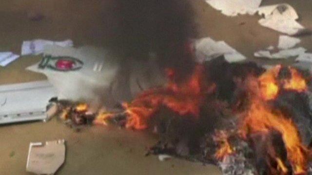 Smashed ballot box and burning voting papers