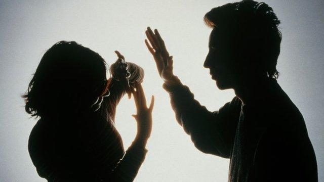 Silhouette of a man striking a woman