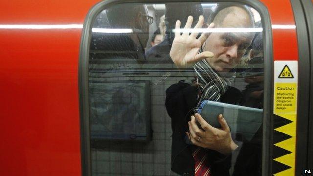 A passenger is squeezed up against a door in one of the few tube trains which became overcrowded during rush hour at Oxford Circus