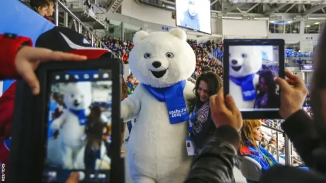 A woman poses with a Sochi Olympic mascot at the ice hockey arena