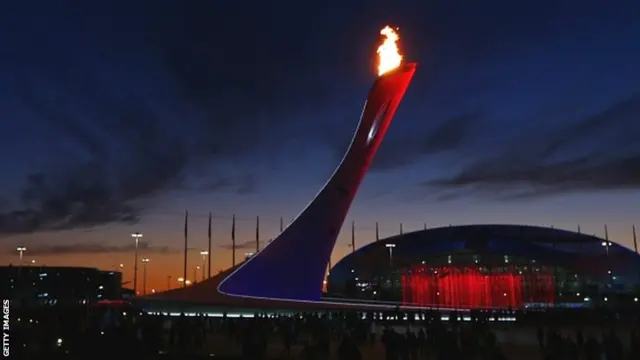 The Olympic Cauldron burns in front of the Bolshoy Ice Dome and Shayba Arena