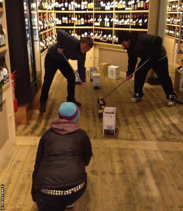 Staff at a Manchester off licence play curling on their shop floor