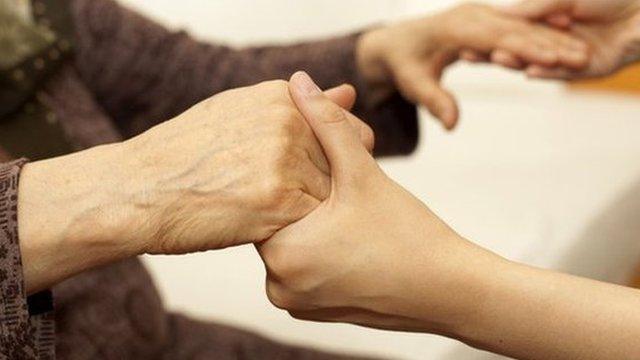 Old person holding hands with carer