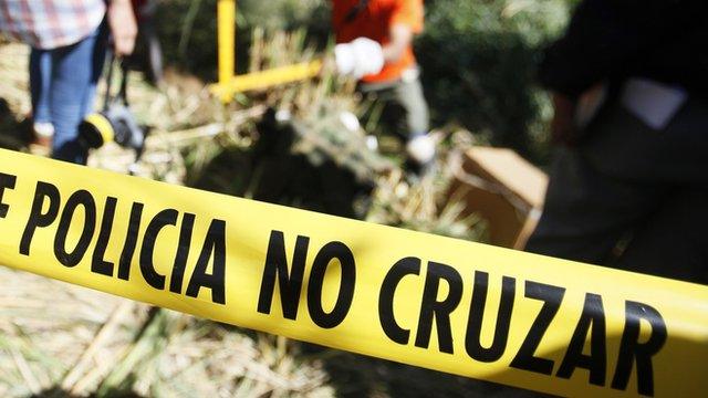 Police tape is seen around a cordoned off area where forensic technicians work during an exhumation at a hidden mass grave discovered in Lourdes, El Salvador