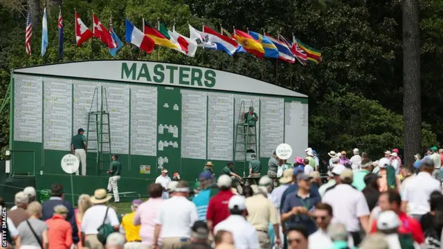 Patrons walk in front of the leader board