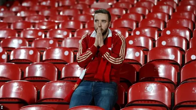 A Liverpool fan sits alone dejected in the stands