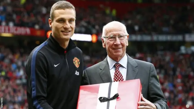 Manchester United's Nemanja Vidic receives a present from former Manchester United player Bobby Charlton