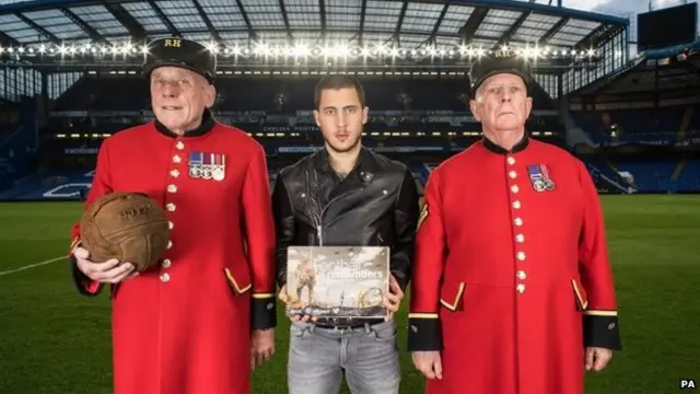 Chelsea and Belgium footballer Eden Hazard with Chelsea pensioners Steve Lovelock (left) - holding a football - and Dave Thomson (right) at Stamford Bridge football ground, London