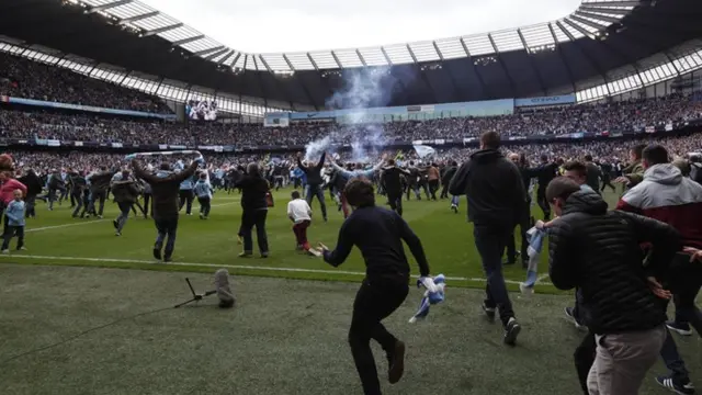 Manchester City fans runs onto the pitch at the Etihad Stadium