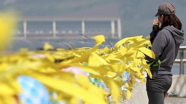 A volunteer wipes away tears near yellow ribbons with messages for the victims and missing passengers of the sunken ferry Sewol at a port in Jindo, south of Seoul, South Korea, 12 May 2014