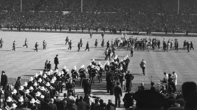 A marching band heads onto the pitch at Wembley after England's 1966 World Cup final win