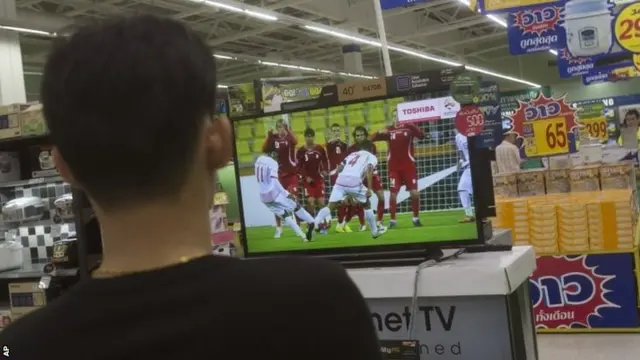 Man watches football on television in Bangkok