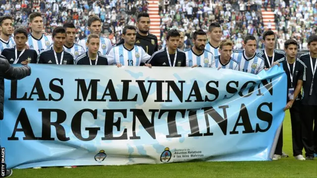 Argentina's footballers pose for photographers holding a banner reading 'The Malvinas / Falkland Islands are Argentine'