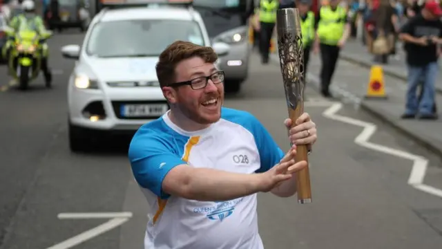 Michael Mair waves to the crowds as he carries the baton through the streets of Edinburgh