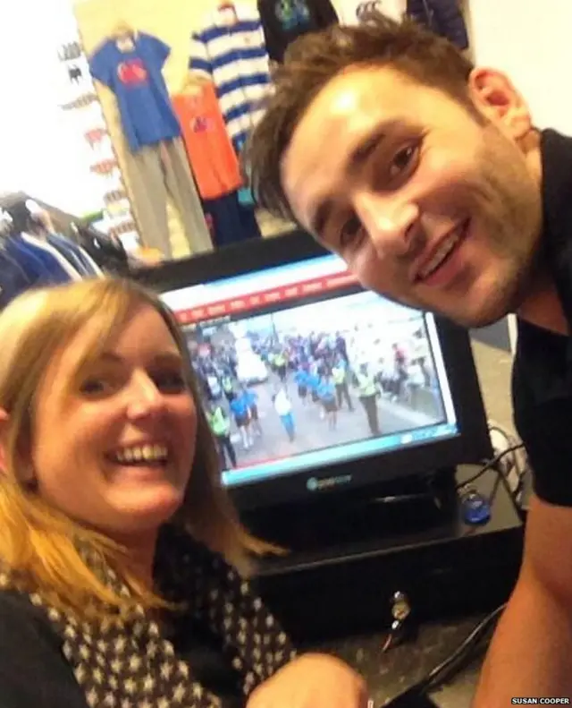 Two smiling people in front of a computer screen showing the BBC live page