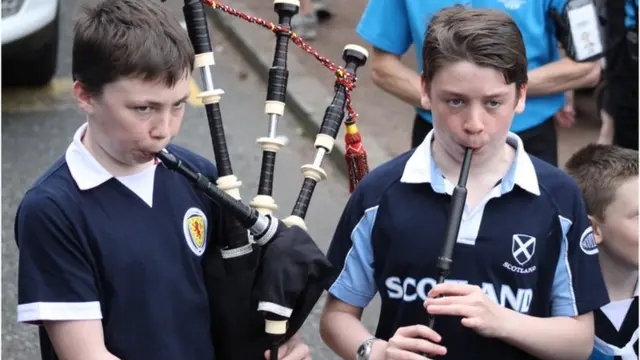 Two boys in Scotland tops playing bagpipes