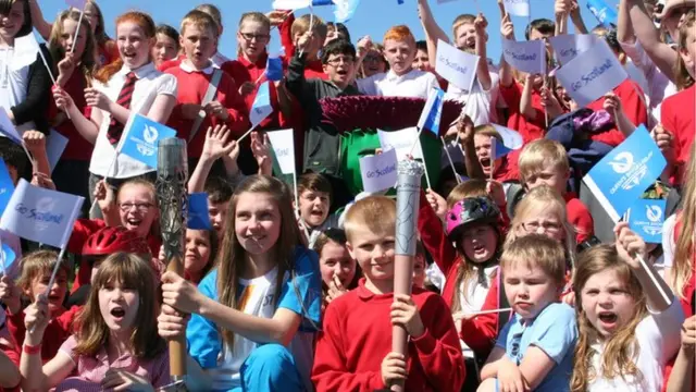 Crowd shot of happy children waving replica Queen's batons