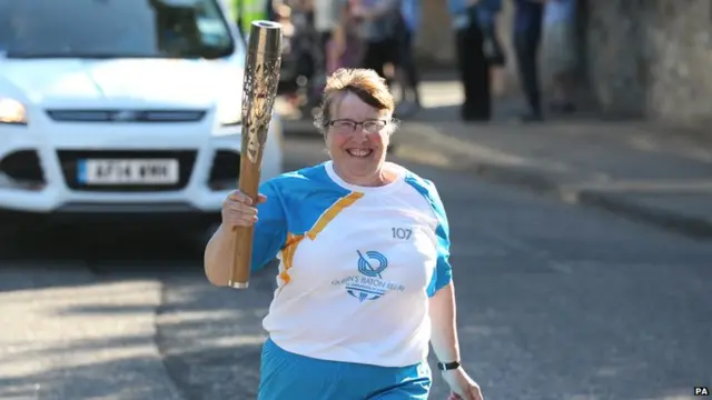 Margaret Kerr runs with baton and a huge smile on her face