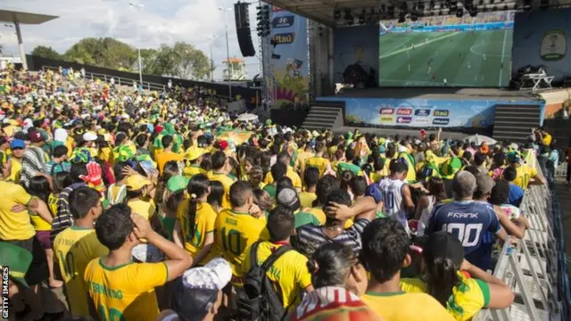 Fans of the Brazilian football team watch a match on a giant screen in the "Fan Fest" area