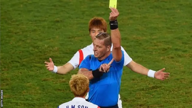 Son Heung-Min of South Korea is shown a yellow card