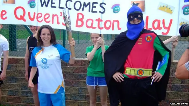 Baton bearer next to man in superhero outfit