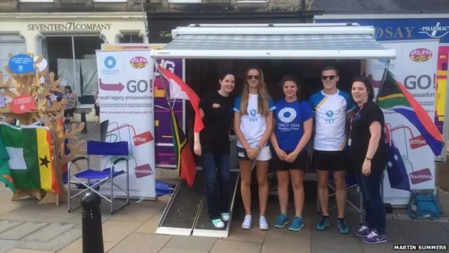 Young people pose in front of a promotional stand