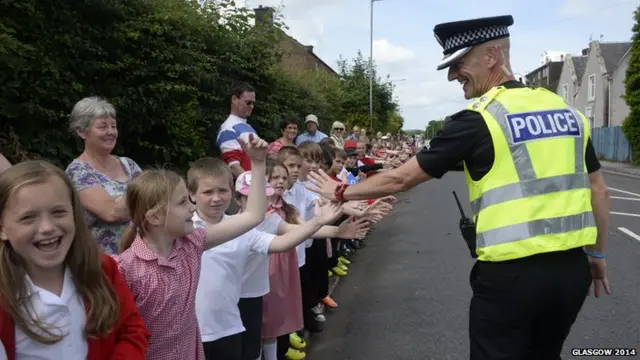 A policeman greets schoolchildren as they welcome the Glasgow 2014 Queen's Baton through Dumfries