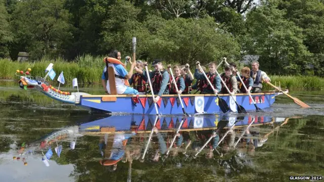 Kirsten Gair carries the Glasgow 2014 Queen's Baton on a canoe at Carlingwark Outdoor Centre in Dumfries & Galloway.