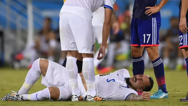 Konstantinos Mitroglou lies injured in the game against Japan