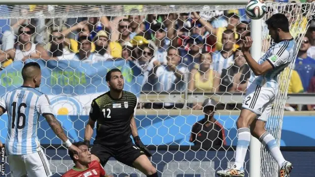 Iran's goalkeeper Alireza Haqiqi defends as Argentina's defender Ezequiel Garay