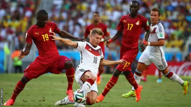 Toni Kroos of Germany is challenged by Jonathan Mensah and Mohammed Rabiu of Ghana