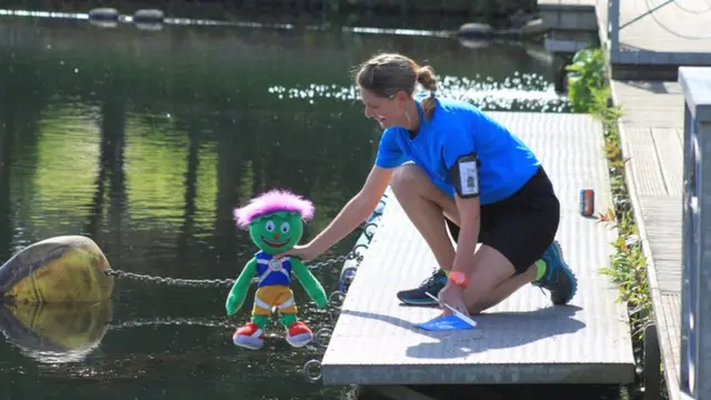 A member of the Queen's Baton Relay security team takes the Commonwealth Games mascot, Clyde, for a dip in Lanark Loch.