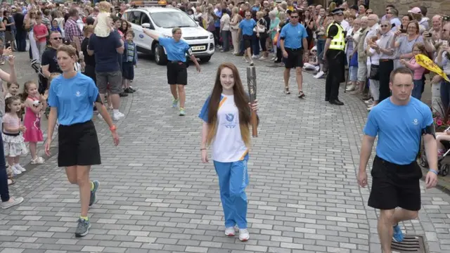 Young woman carries Queen's baton through large crowd