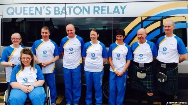 Group photo of eight baton bearers at side of bus