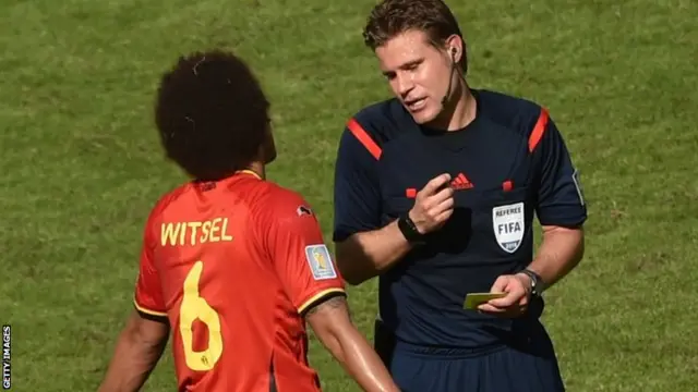 Belgium's midfielder Axel Witsel protests as he is issued a yelow card